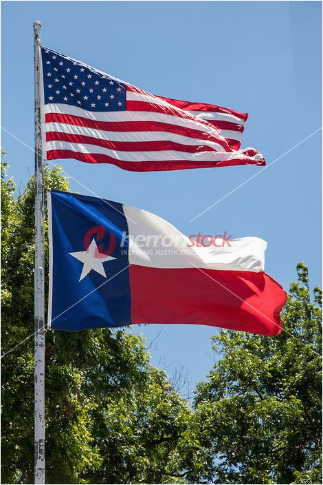 u s and texas flag on a flag pole flying in the bre texas lone